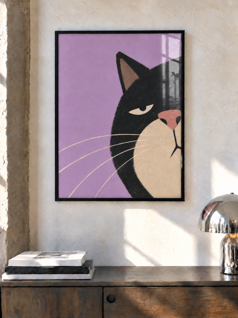Black-framed portrait of a black cat on lilac, hanging above a dark wooden sideboard beside a chrome lamp.