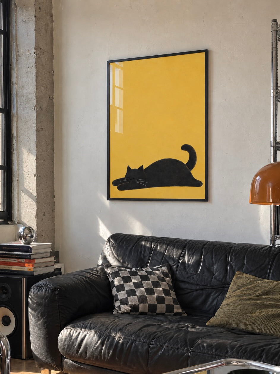 No Rush black cat art print in a black frame above a black leather sofa in a sunlit living room