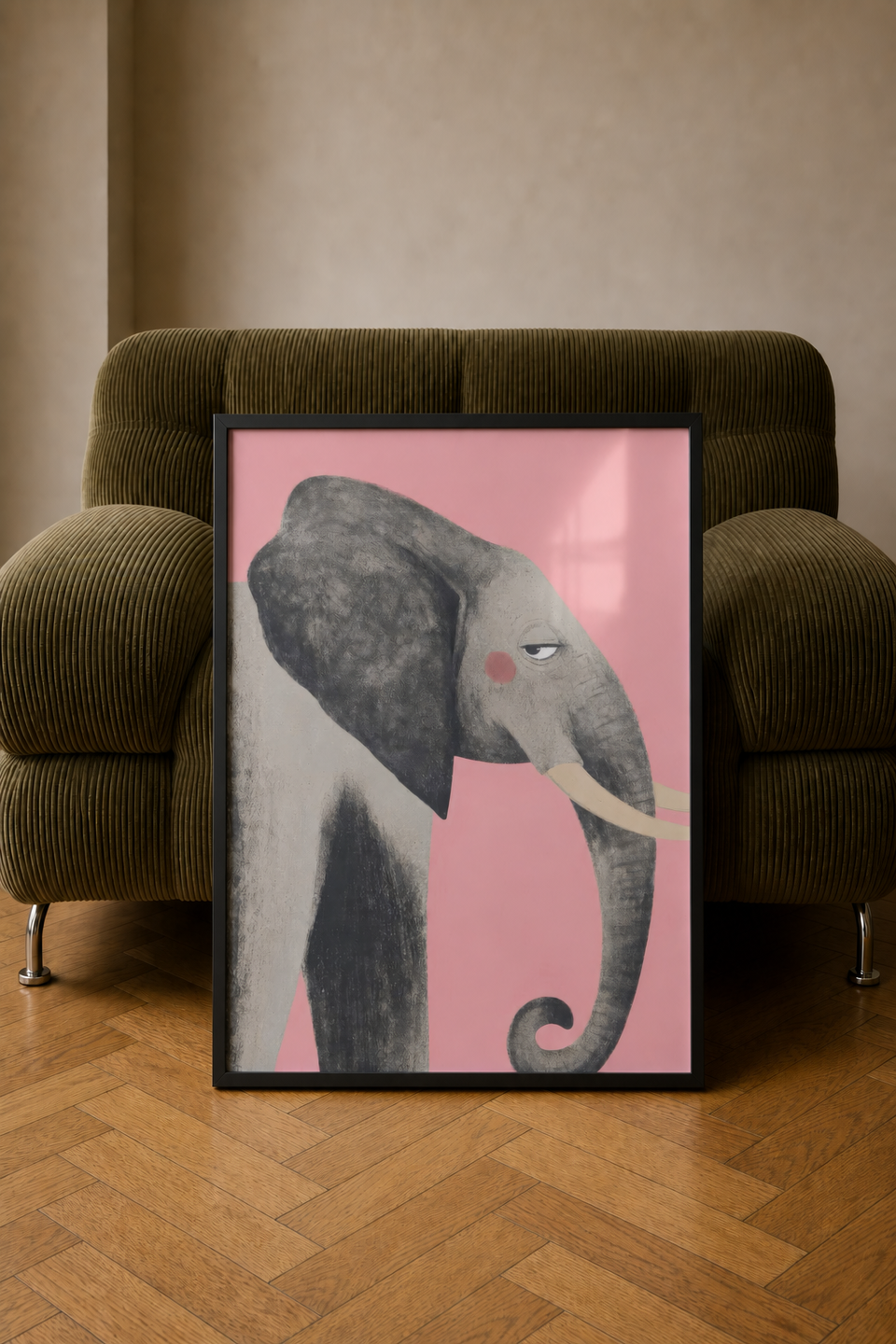 Framed Elephant 2 art print leaning against an olive-green corduroy armchair on a wooden floor