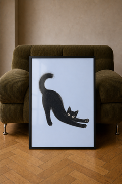 Framed Big Stretch art print leaning against an olive-green corduroy armchair on a wooden floor